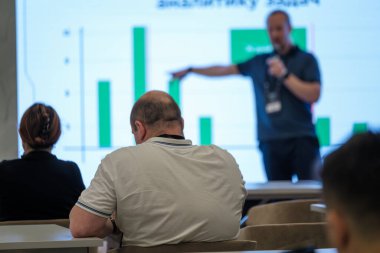 Profesyonel konuşmacı, bir iş semineri ortamında özenli bir izleyiciye etkileyici veri görselleştirmeleri sunuyor. Eğitim ve mesleki gelişim ortamı etkili bir şekilde ele geçirildi.