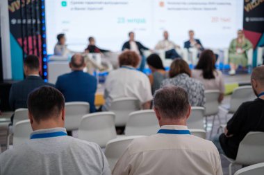 Kürsüde oturan katılımcılar, uzmanların iş seminerinde görüşlerini paylaşmalarını dinliyor