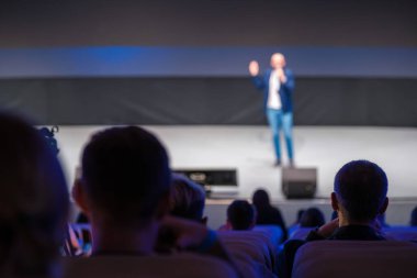 Seyirci, iş konferansı ortamında dinamik atmosferle sahnede sunan konuşmacı görüşü.