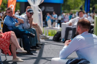 Açık hava paneli tartışması sıradan bir ortamda seyirciyi meşgul ediyor. Doğal gün ışığı atmosferi güçlendirir.