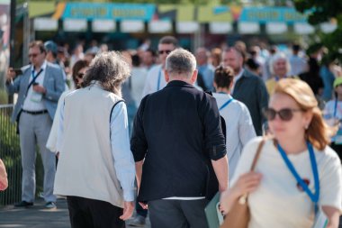 Kalabalık bir açık hava etkinliğinde yürüyen bir grup insan sosyal etkileşimler ve bağlantılar sergiliyor.