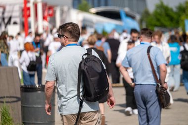 Canlı aktivite ve etkileşimle çevrili güneşli hava koşulları altında kalabalığın içinde yürüyen profesyonellerin yer aldığı ağ etkinliği.