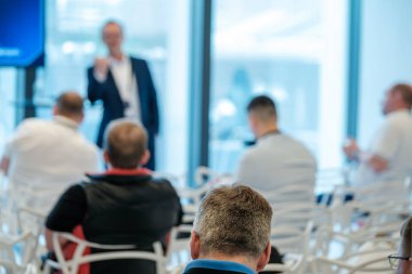 Modern mekandaki şirket etkinliği sırasında doğal ışıklandırmayla katılımcılara hitap eden profesyonel konuşmacı