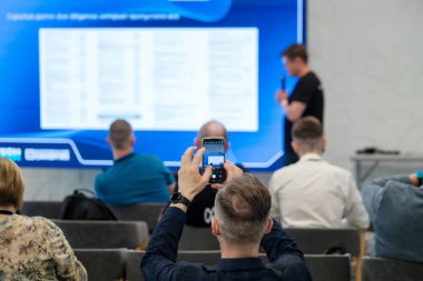 Katılımcı ekranın fotoğrafını çekerken, bir atölye çalışması sunumuna katılanlar