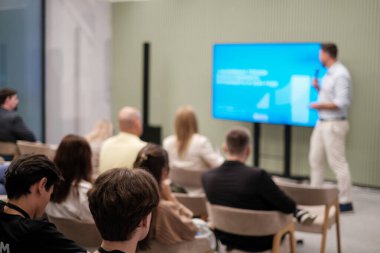 Seyirciler çağdaş bir seminer ortamında konuşmacı sunumunu dinliyorlar..
