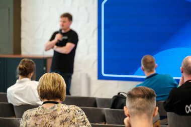 Profesyonel bir ortamda bir atölye çalışması sırasında oturmakta olan izleyicilere sunum yapan konuşmacı