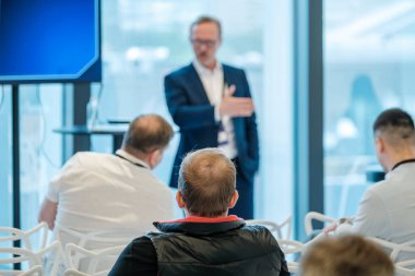 Sunucu, iş sunumu sırasında iş ortamında seyircilerle fikirleri tartışıyor