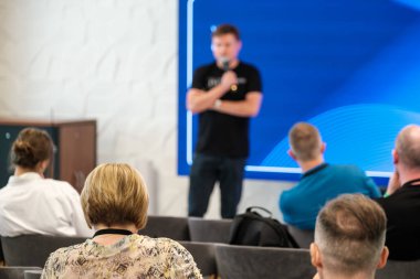 İş seminerinde izleyicilerle birlikte sunum yapan konuşmacı, öğrenme ve katılım atmosferini ön plana çıkarıyor