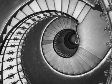 Yukarıdan tek renkli bir tonda, zarif sarmal merdiven. Karmaşık korkuluk tasarımı ve zarif mimari kıvrımlar..