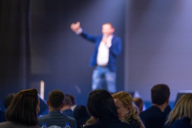 Koridorda dikkatle dinleyen bir seyirciyle iş toplantısında konuşma yapan bir adam..