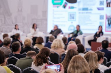 Katılımcılar, konuşmacıların fikir ve konuları sunduğu bir konferans panelini izliyor