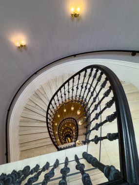 Süslü demir korkuluklar ışıklı sarmal merdivenleri sarar zarif yükseklik ve derinlik yaratır