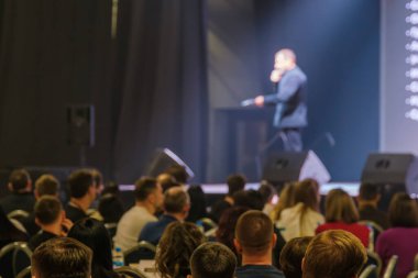 Konuşmacı seyircilere sunumu yaparken kalabalık konferansa katılıyor