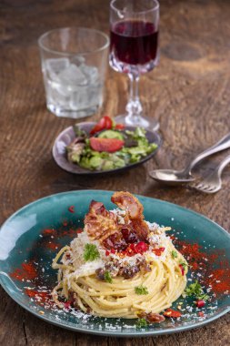 Spagetti carbonara, salata ve odun.