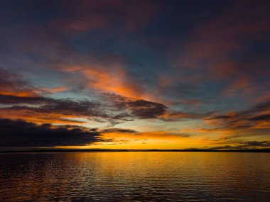 Bir göl ya da okyanus gibi büyük bir su kütlesinin üzerinde dramatik bir gün batımı.