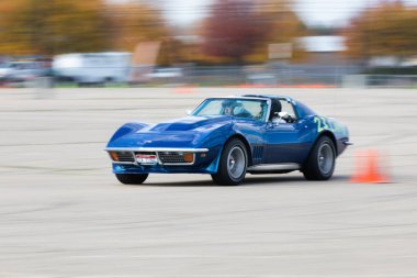 Boise, Idaho - 31 Ekim 2021: Klasik bir mavi Corvette yarış pisti etrafında hız yapar, yarışın heyecanını vurgulamak için hareket bulanıklığıyla tasvir edilir. Sahne heyecan ve dinamik enerji yayar..
