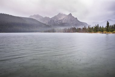 Sis kaplı ormanlarla çevrili sakin bir dağ gölü ve sakin, bulutlu bir atmosferde yükselen zirveler doğanın dokunulmamış güzelliğini gözler önüne seriyor..