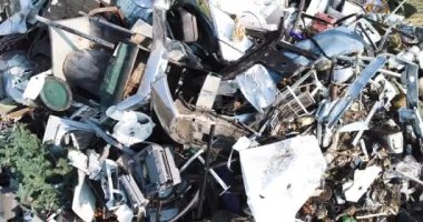 Arızalı bir televizyon ve bozuk bir buzdolabı da dahil olmak üzere hurda yığını tarafından çekilen yükselen ateş. Yığınlar çöp ve enkaz dolu.