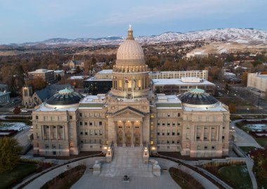 Capitol binası, tepesinde kubbe olan büyük ve süslü bir yapıdır. Çevredeki alan çoğunlukla boş, sadece birkaç araba ve birkaç kişi görülebiliyor. Gökyüzü mavi ve turuncu karışımıdır.