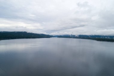 Gökyüzü bulutlu ve su sakin. Bulutların yansıması suda görülebilir.