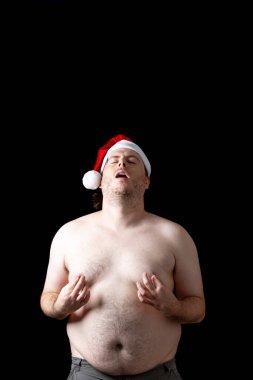Kafasında Noel Baba şapkası olan bir adam komik bir surat yapıyor.