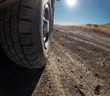 Bir çöl manzarasının ön planında bir lastik gösterilir. Lastik siyah ve beyaz kenarlı. Macera ve keşif kavramı. Lastik muhtemelen off-road seyahatlerinde kullanılan bir araçtan.