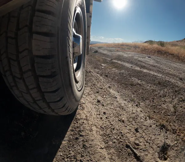 Bir çöl manzarasının ön planında bir lastik gösterilir. Lastik siyah ve beyaz kenarlı. Macera ve keşif kavramı. Lastik muhtemelen off-road seyahatlerinde kullanılan bir araçtan.