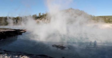 İçinden buhar çıkan büyük bir su kütlesi. Buhar beyaz ve su mavi.