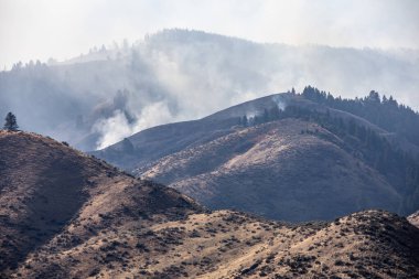 Havada duman olan bir dağ sırası. Duman yangından geliyor.