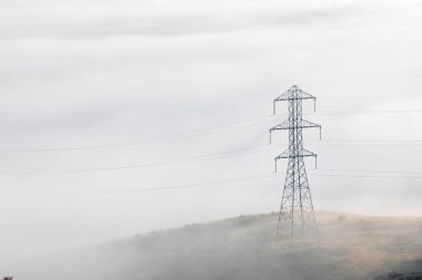 Uzun bir güç kulesi sisli bir gökyüzüyle çevrilidir. Görünürdeki tek nesne güç kulesi.