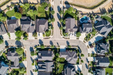 Evleri ve caddeleri olan bir mahalle. Evlerin hepsi farklı boyutlarda ve tarzlarda. Sokak ağaçlarla kaplı ve kaldırımı var.