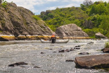 Bir adam kayalarda oturuyor ve kameraya bakıyor.