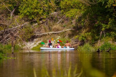 Parktaki nehirde bir grup insan. 
