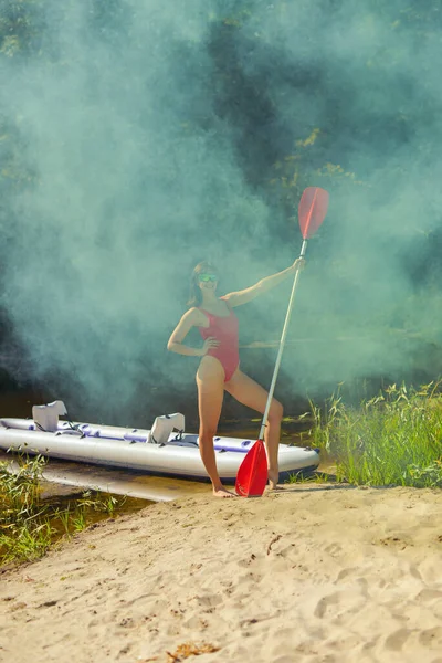 身穿泳衣和红色比基尼的女人拿着桨板做背景 — 图库照片