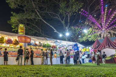 Bangkok, Tayland - 8 Aralık 2022: 8-18 Aralık 2022 tarihleri arasında Kızılhaç Fuarı 'nı ziyaret edenler renkli oyuncak bebekler kazanmak için havalı tüfekler ateşliyorlar. Güzel ışıklar. Hareket bulanıklığı.