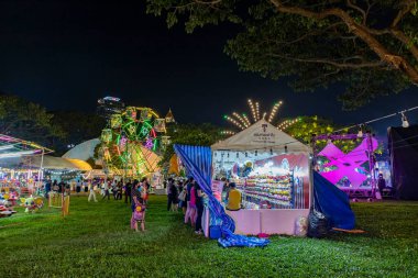 Bangkok, Tayland - 8 Aralık 2022: 8-18 Aralık 2022 tarihleri arasında Kızıl Haç Fuarı sırasında güzel aydınlatılmış bir eğlence parkına bir kalabalık girer. Görüntü hareketle bulanıklaşıyor..