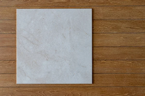 stock image Light gray square marble sign Hanging on a brown horizontal plank wall Or you can look at it as a marble tray placed on a wooden floor taken from above. up to imagination There are many copy spaces.