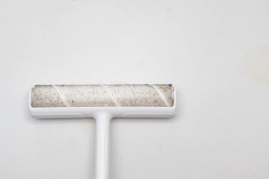 Yerleri temizlemek için kürk yakalamak için yapışkan yapışkan patenli kafa. Bir sürü tüy ve saç çeşidi var. Toz, enkaz vs. gibi diğer kirleri de yakalayabilir. Beyaz beton duvarlarda ışık lekeleri var..