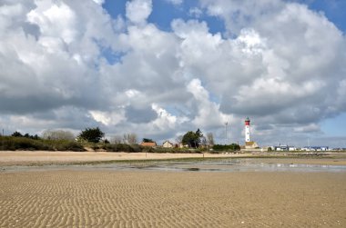 Fransa 'nın kuzeybatısındaki Basse-Normandie bölgesinde Calvados bölgesinde bir komün olan, bulutlu bir gökyüzü olan Ouistreham' da deniz feneri ve deniz fenerinde sahil..