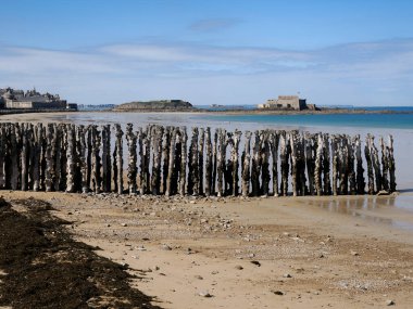 Saint Malo 'nun Sillon plajı ve meşe yığını dalgaları. Fort National 'ı uzaktan görebiliyoruz. Saint-Malo, Britanya 'nın kuzey kıyısında, Ille-et-Vilaine ilinde yer alan bir Fransız komünü.