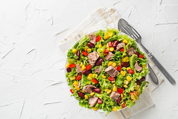 Healthy Green salad with tuna, corn, pepper and beans on white table background. Mexican corn salad.