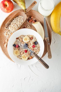 Taze meyve ve fındık ile servis edilen bir kase kuru granola ve müsli. Yulaf ezmesi. Sağlıklı yiyecekler, diyet. Üst görünüm.