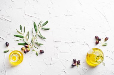 Taze zeytin meyveli zeytin yağı şişeleri ve beyaz arka planda zeytin dalı.
