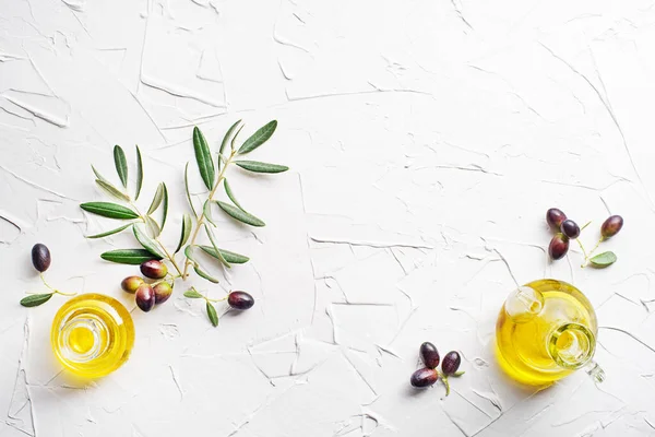 Olive oil bottles with fresh olives fruit and olive branch on white background close up