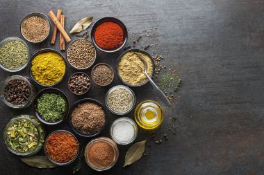 Colorful herbs and spices for cooking. Indian spices. On grey stone background. Top view.