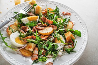 Dandelion salad with egg bacon potato and croutons close up clipart