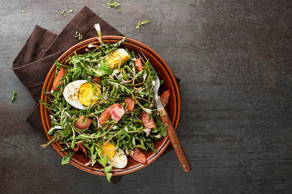 卵とローストベーコンとタンポポのサラダグレーの背景 — ストック写真