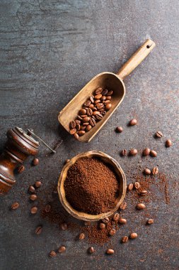 Coffee beans and freshly ground coffee powder on grey stone background close up