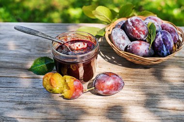 Güneşli bir günde açık havada erikli meyve dolu cam kavanozda erik reçeli ya da marmelat