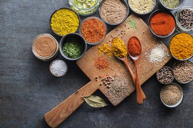 Yemek pişirmek için renkli otlar ve baharatlar. Gri taş arka planda Hint ve Asya baharatları. Üst görünüm.